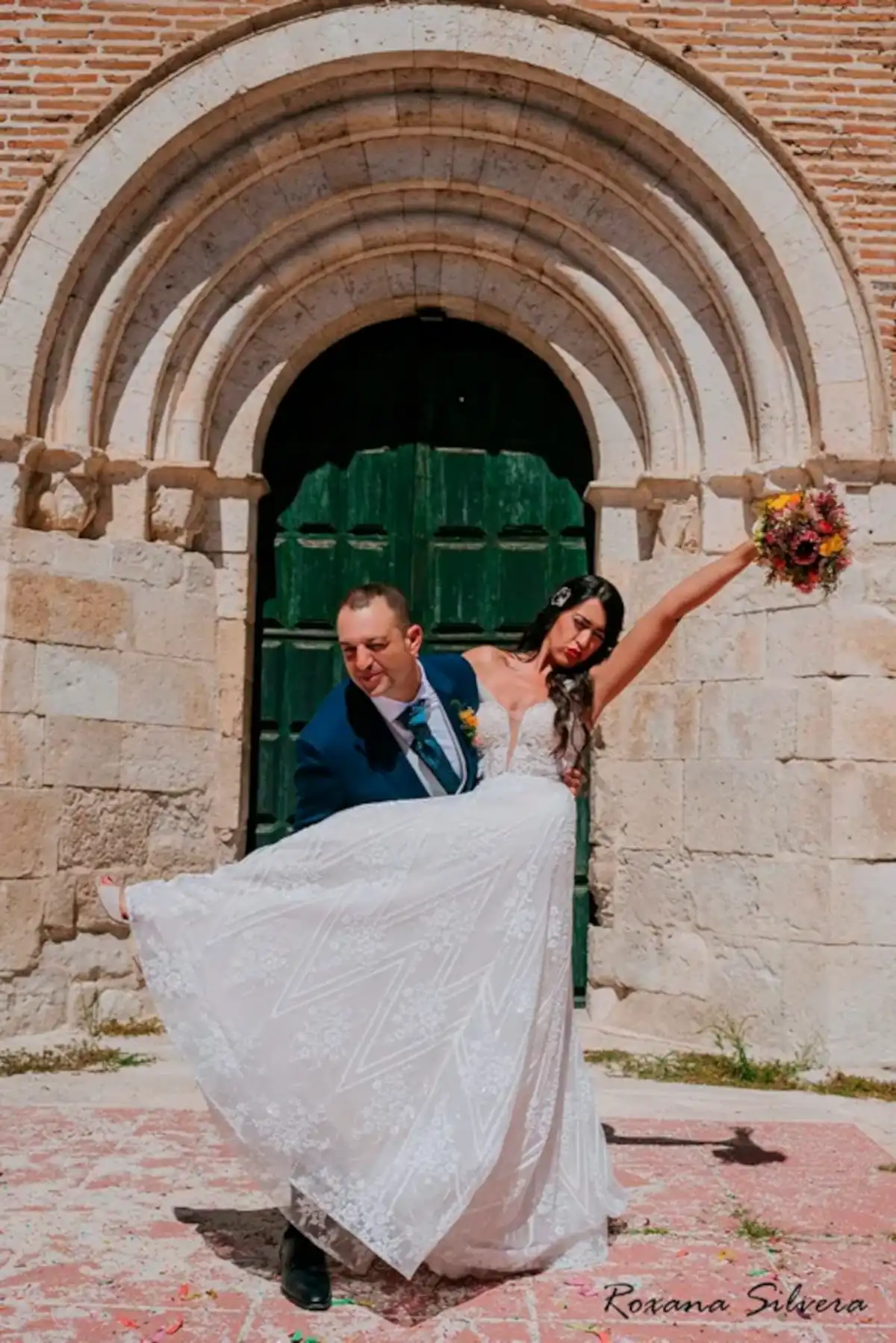 Novios posando felices a la puerta de la iglesia el día de su boda