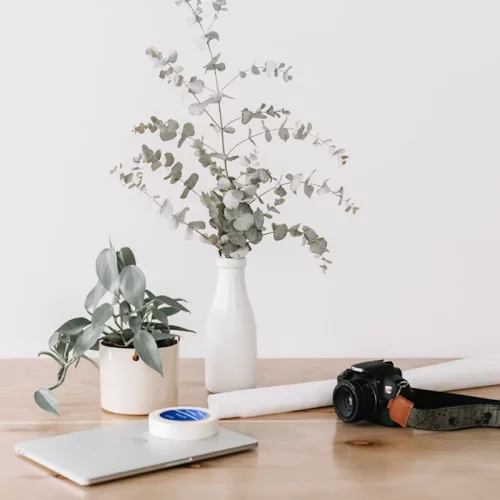 Cámara y portátil sobre mesa en composición artística